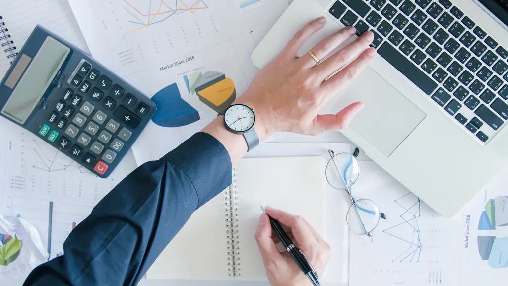 Hand on a desk with a laptop, calculator and documents Hand on a desk with a laptop, calculator and documents